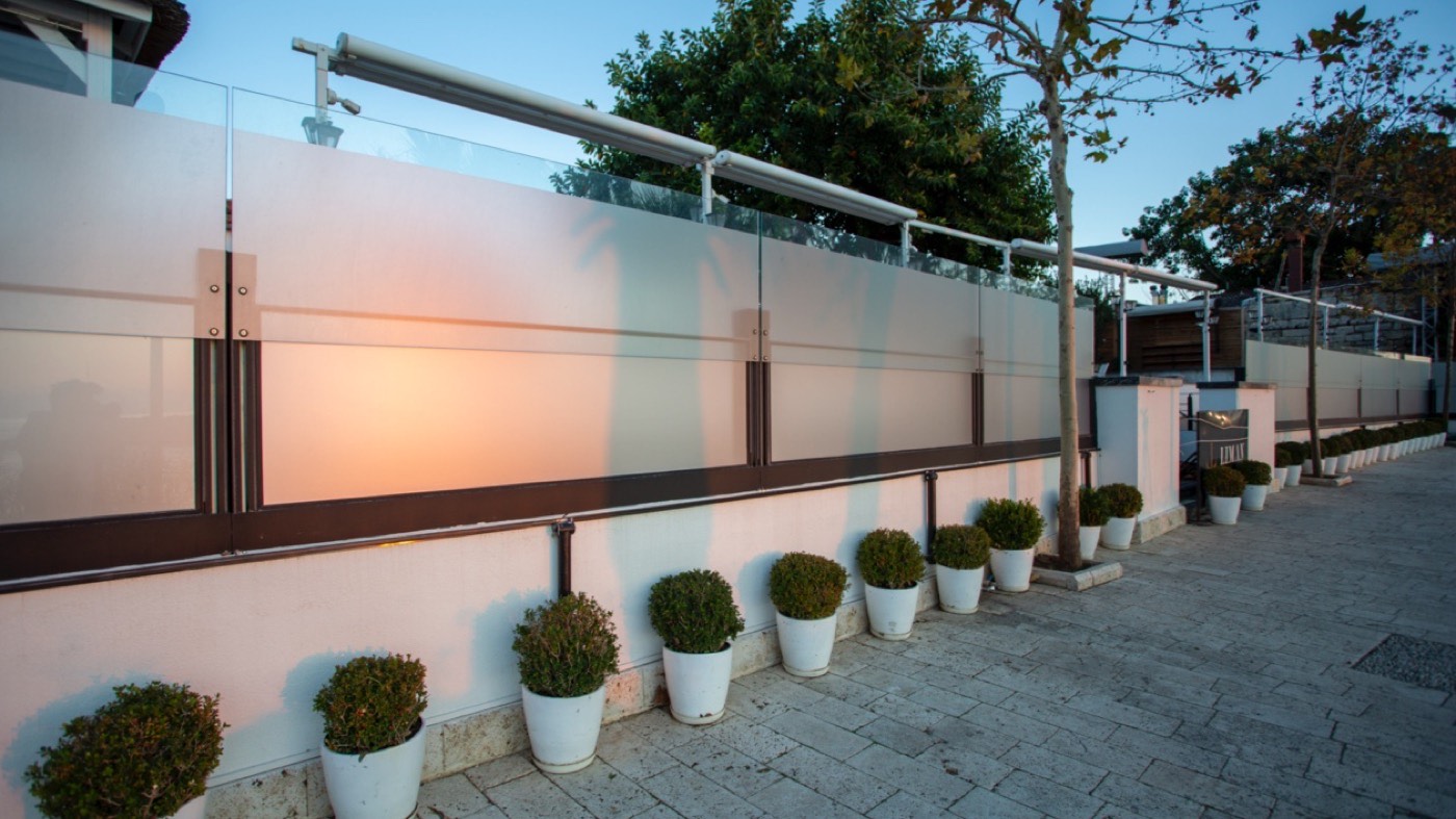 Höhenverstellbarer Windschutz aus Glas an einer Außenterrasse
